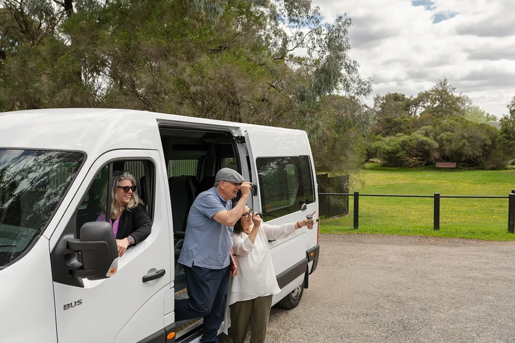 activities for seniors: A smiling group of elderly clients getting out of a white community mini-bus for a BASSCARE social support outing.