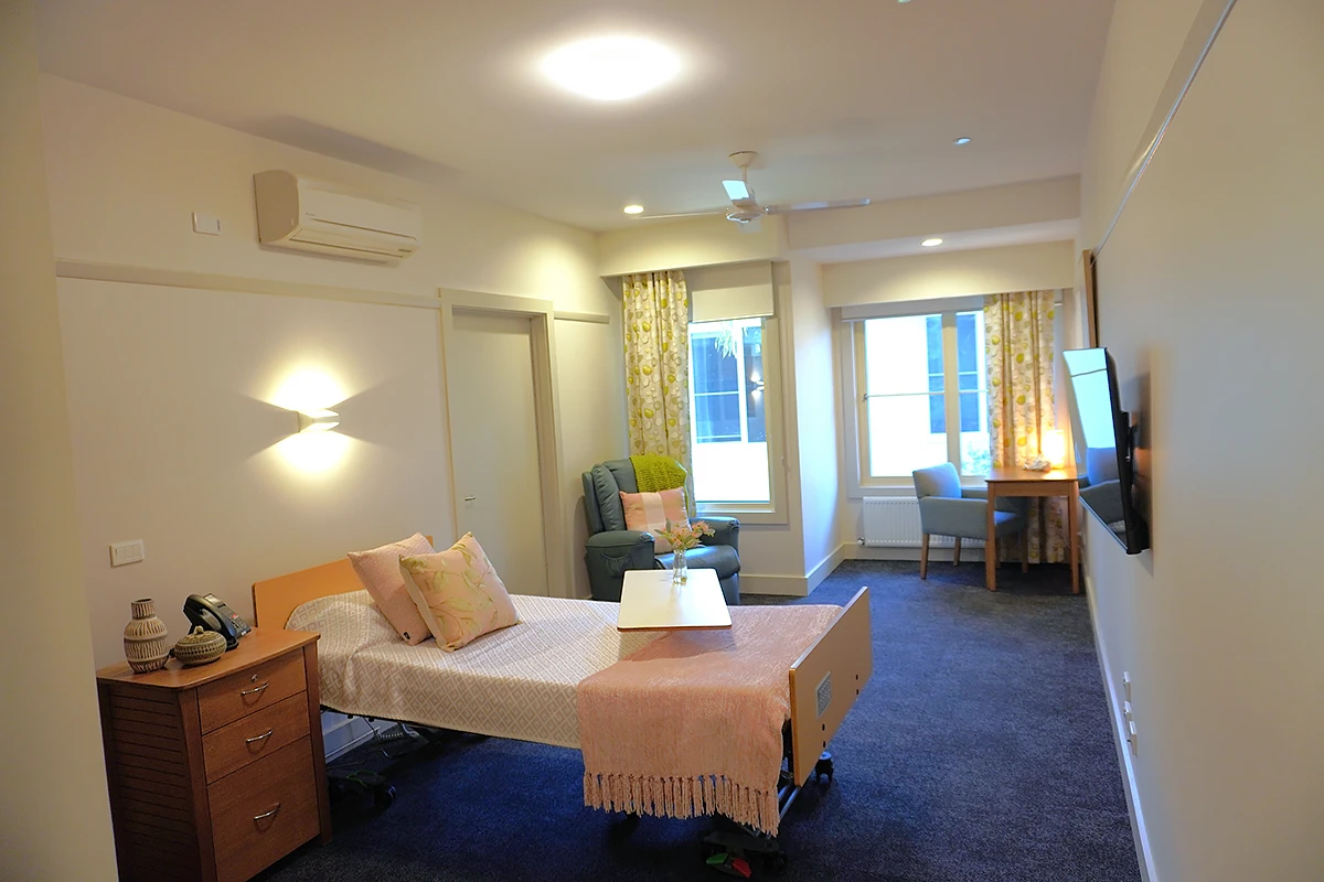 A private resident's room at Samarinda Lodge, BASSCARE's Ashburton residential aged care home, featuring a comfortable bed, armchair, and large window.